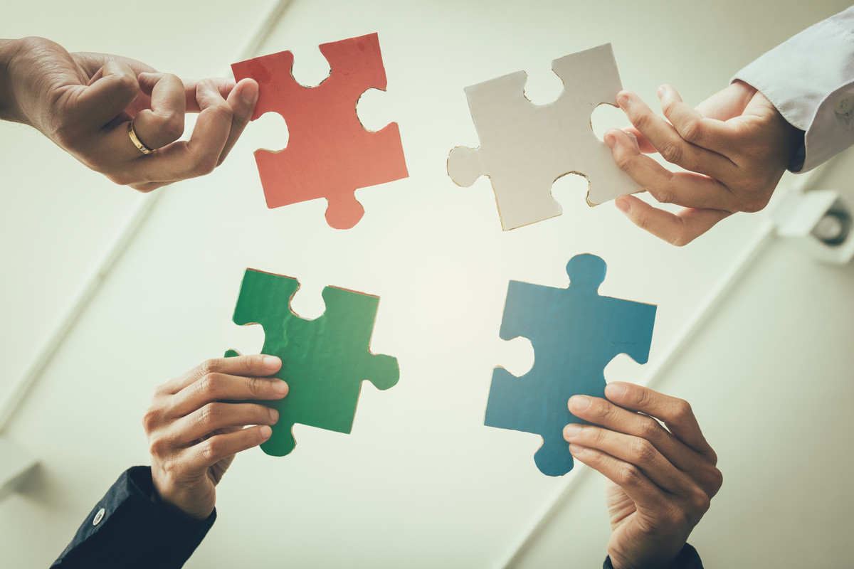 Multi-Ethnic Group of Business Professional Putting Four Puzzle